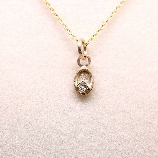 Gold necklace with a pendant on a light pink background